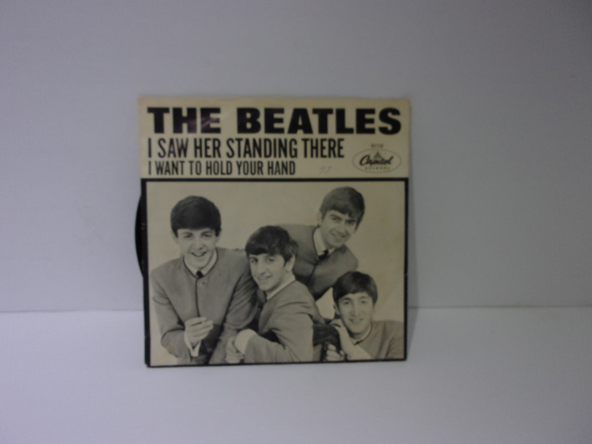 The Beatles: I Want To Hold Your Hand Capitol Records 5112 45RPM single cover featuring a group photo of The Beatles with the titles 'I Saw Her Standing There' and 'I Want To Hold Your Hand'.
