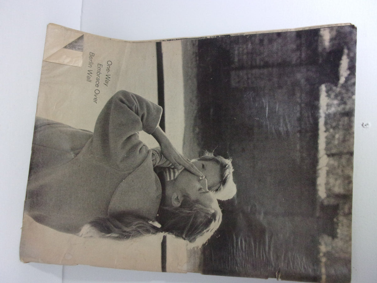 1963 Budweiser Magazine Ad: A Tradition in Hospitality featuring a vintage photograph of a couple embracing near the Berlin Wall, capturing a moment of intimacy and historical significance.