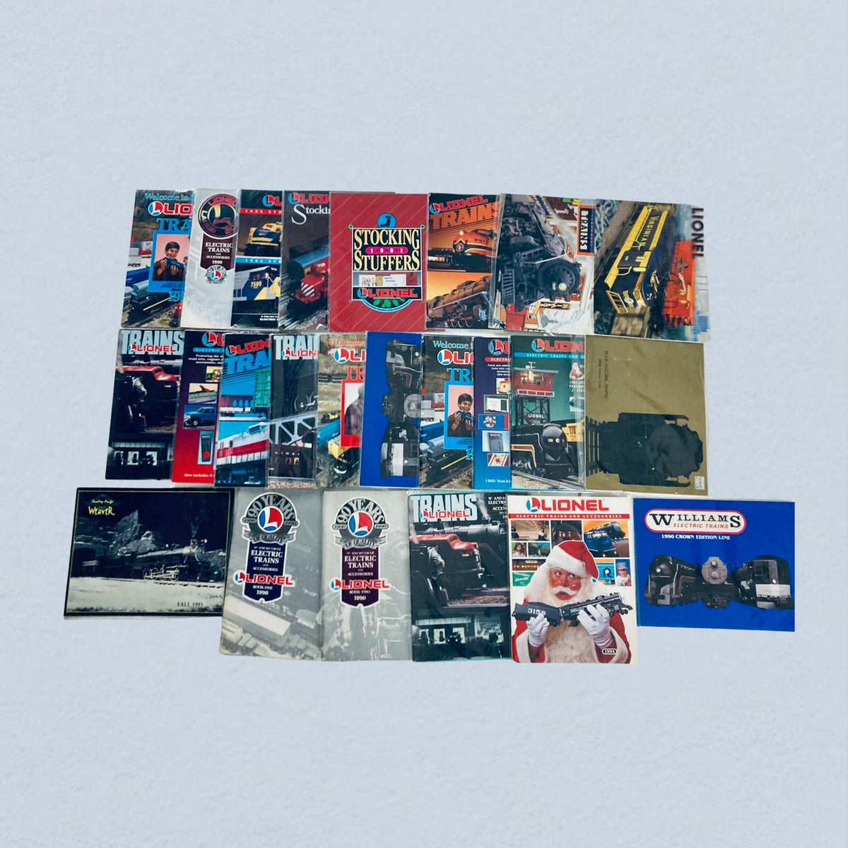 Lot of 24 1990s Lionel Electric Trains and Accessories Catalog, featuring a collection of colorful train catalogs and magazines from the 1990s, showcasing various electric trains and accessories.