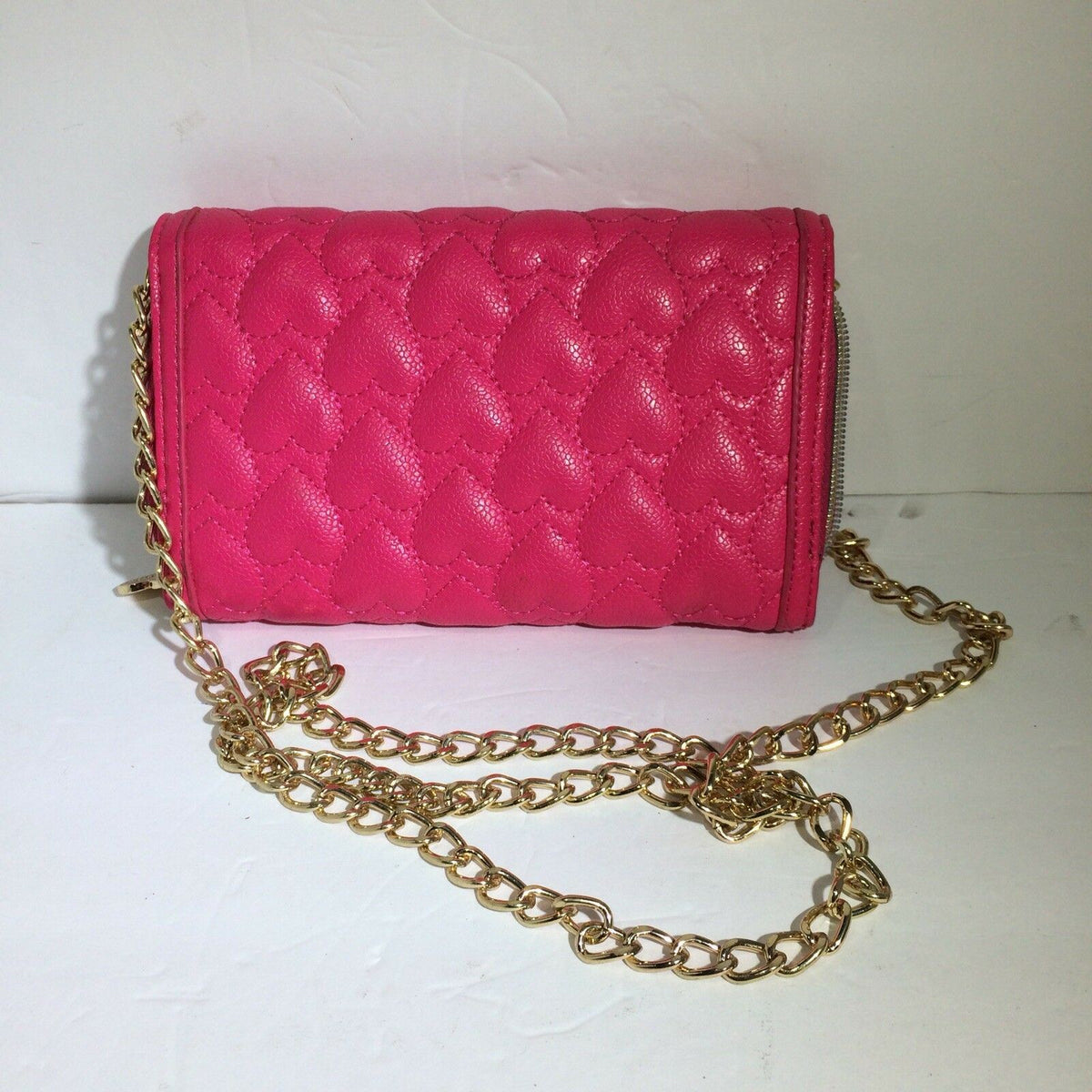 Side view of the Betsey Johnson Pink & Gold Chain Purse Bag Quilted Heart Lock Bow Lipstick, showcasing its pink quilted texture and gold chain strap.
