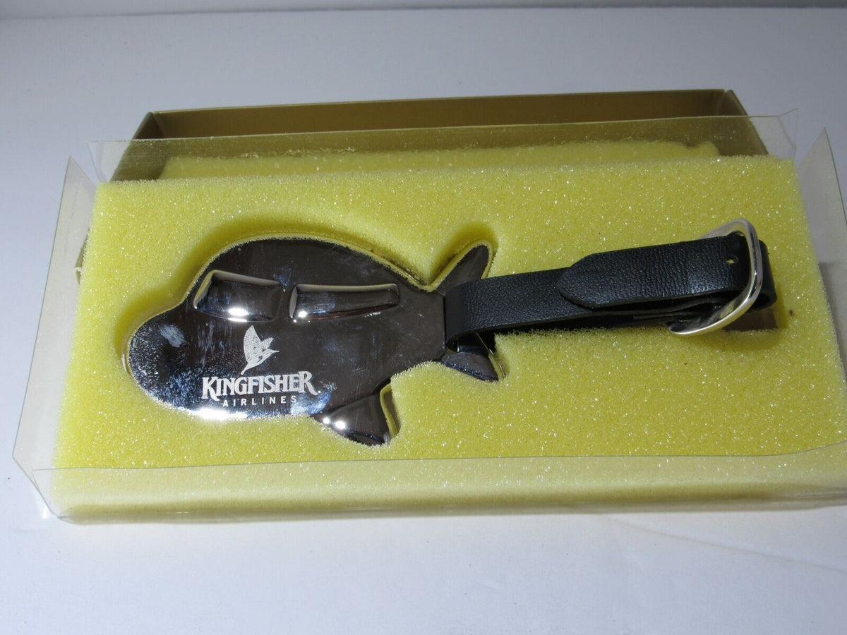 Rare Kingfisher Airlines Luggage Tag First Class Metal Airplane resting on yellow foam, showcasing its distinctive airplane shape and Kingfisher branding.