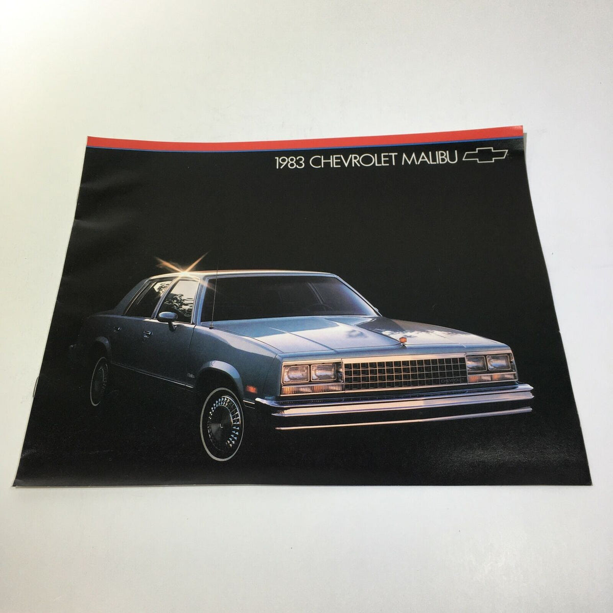 1983 Chevrolet Malibu brochure showcasing the front view of the car in a dark setting, highlighting its classic design.