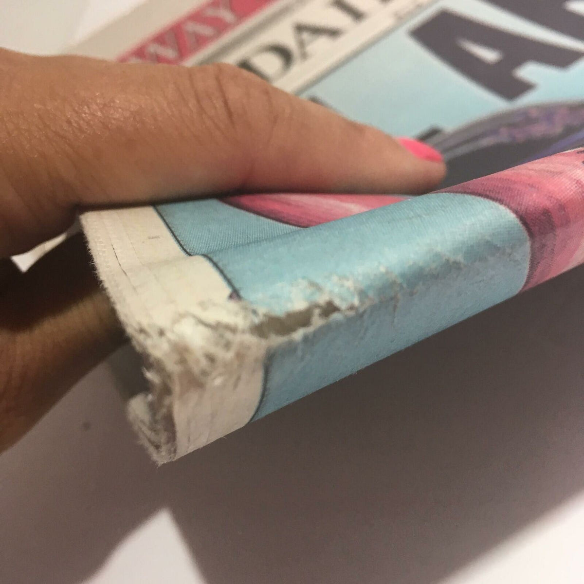 Close-up image of the damaged edge of the NY Daily News: Oct 18 2000 All Aboard! newspaper, showing wear and tear.