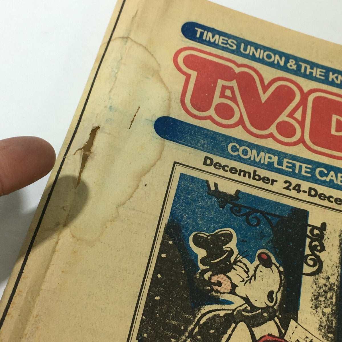 Close-up of the damage on the cover of VTG TV Dial Complete Cable Listings December 24-31 1977, highlighting visible wear and tear including a tear and discoloration.