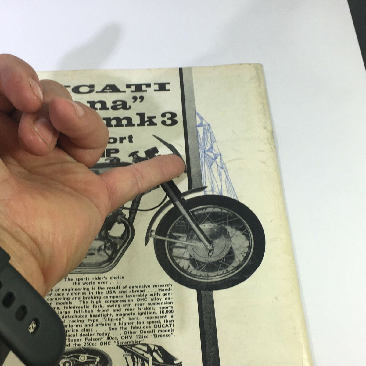 Detail of the VTG Cycle World Magazine September 1963 showcasing a Ducati Mk3 motorcycle with a hand pointing to the cover, highlighting vintage motorcycle design and features.