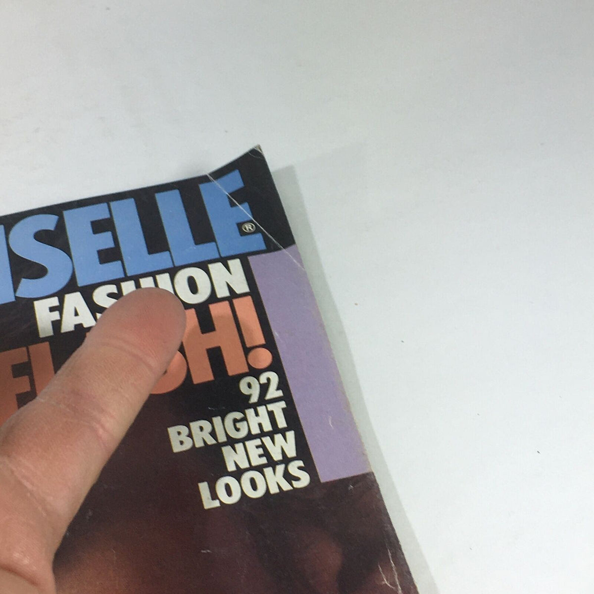 Detail view of the Vintage Mademoiselle Magazine from April 1983, showcasing a corner of the magazine cover with the title 'Mademoiselle' and hinting at its vintage condition and design.