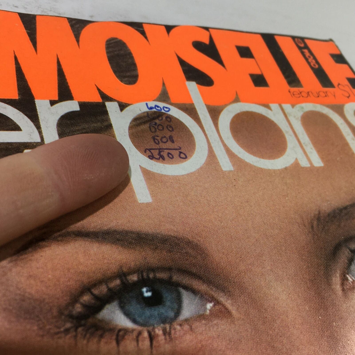 Close-up of the VTG Mademoiselle Magazine: February 1976 cover showing handwritten notes and details near the title, emphasizing the vintage appeal and charm of the publication.