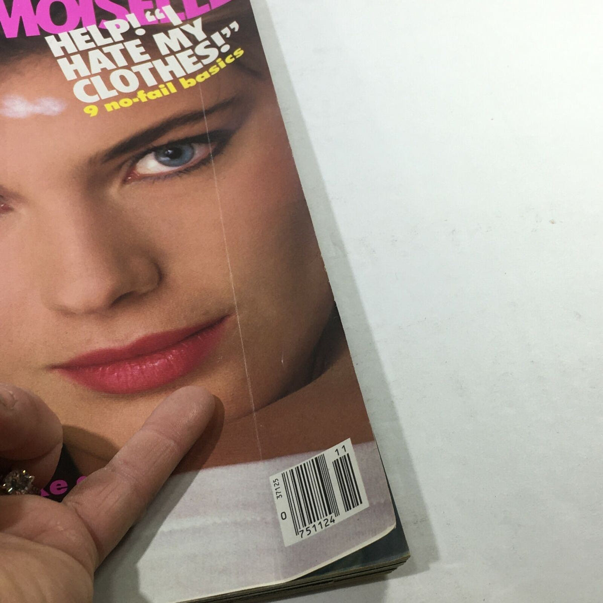 Side view of VTG Mademoiselle Magazine: November 1983 displaying a close-up of the model's face along with a barcode. This image captures the vintage appearance of the magazine, emphasizing its 80s fashion insights.