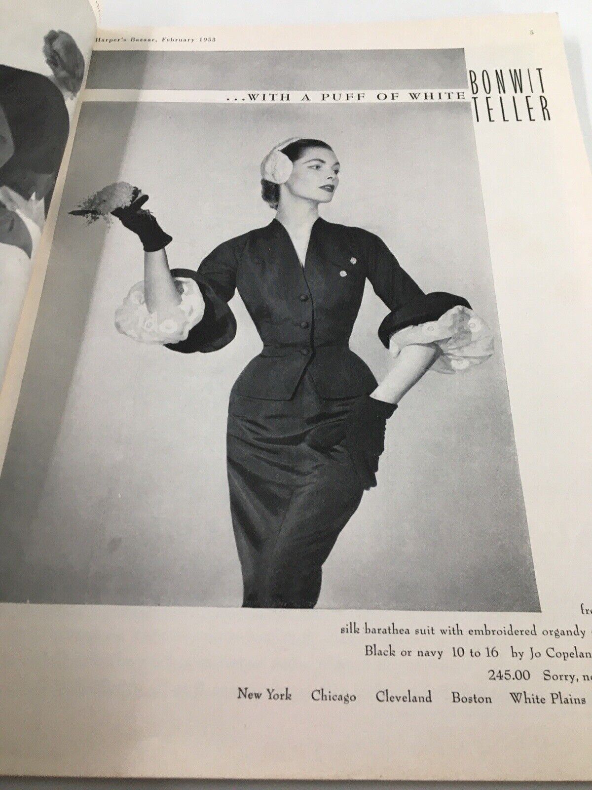 Image from the February 1953 issue of Harper's Bazaar featuring a model in elegant attire with '...WITH A PUFF OF WHITE' caption, emphasizing timeless fashion.