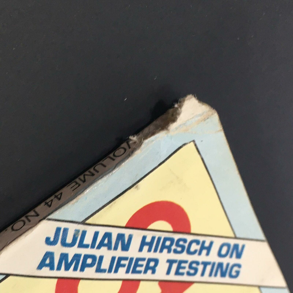 Close-up detail of a vintage magazine from June 1980, titled 'Stereo Review', showcasing a damaged corner with title text featuring 'Julian Hirsch on Amplifier Testing'. This magazine features renowned critic Steve Simels and musician Mark Knopfler.