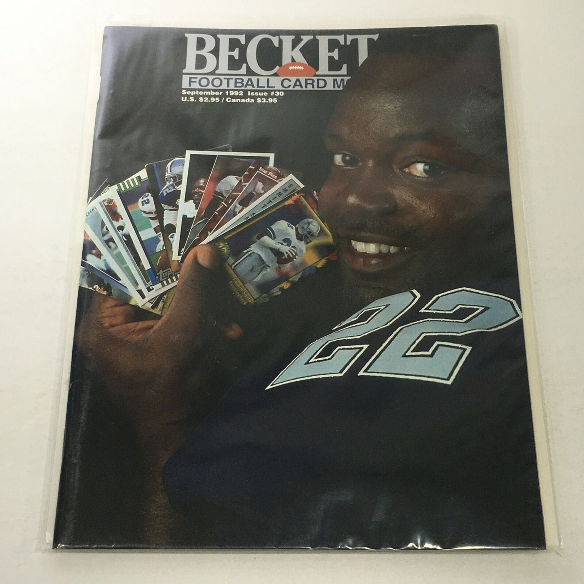 Beckett Football Card Monthly: September 1992 Issue #30 featuring Emmitt Smith, showcasing a smiling man holding multiple football cards, highlighting collectibles in excellent condition.