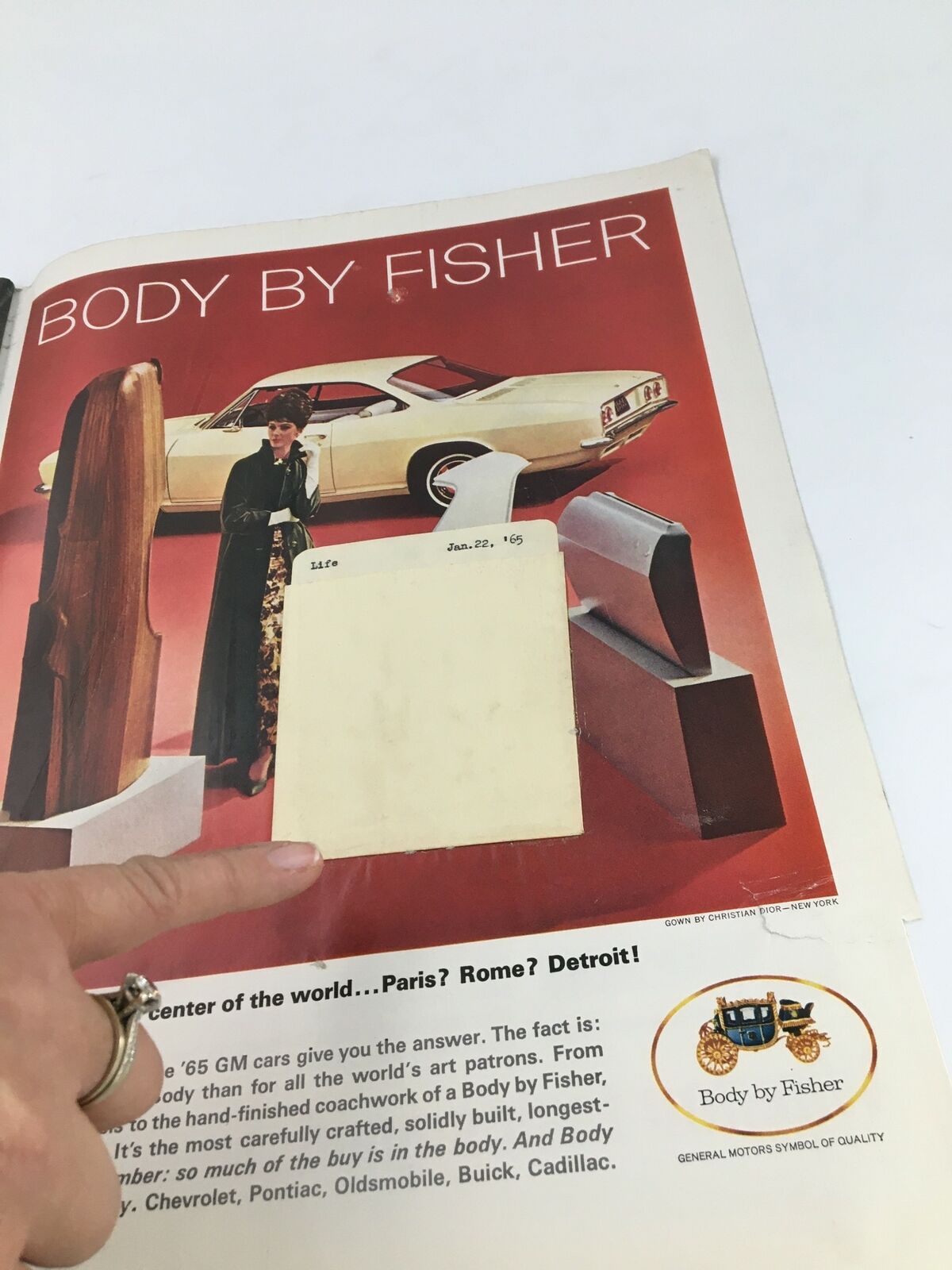 Vintage advertisement from Life Magazine January 22, 1965, featuring a woman in a stylish gown alongside classic cars, showcasing the tagline 'Body by Fisher', emphasizing automotive craftsmanship.