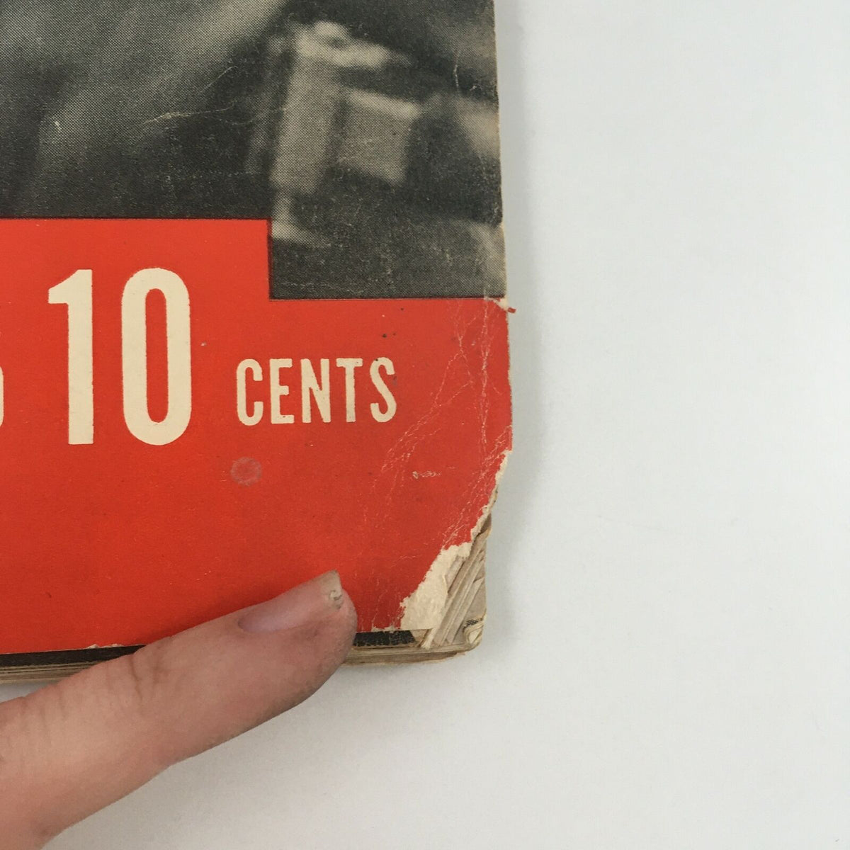 Close-up of the corner of the vintage Life Magazine from May 6, 1940 featuring a photograph of an aerial gunner, showing minor wear with a ripped edge and finger for scale.