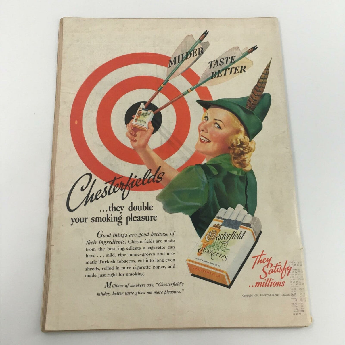 Vintage advertisement for Chesterfield cigarettes from 1938, featuring a smiling woman aiming arrows at a target, promoting the slogan about milder taste.