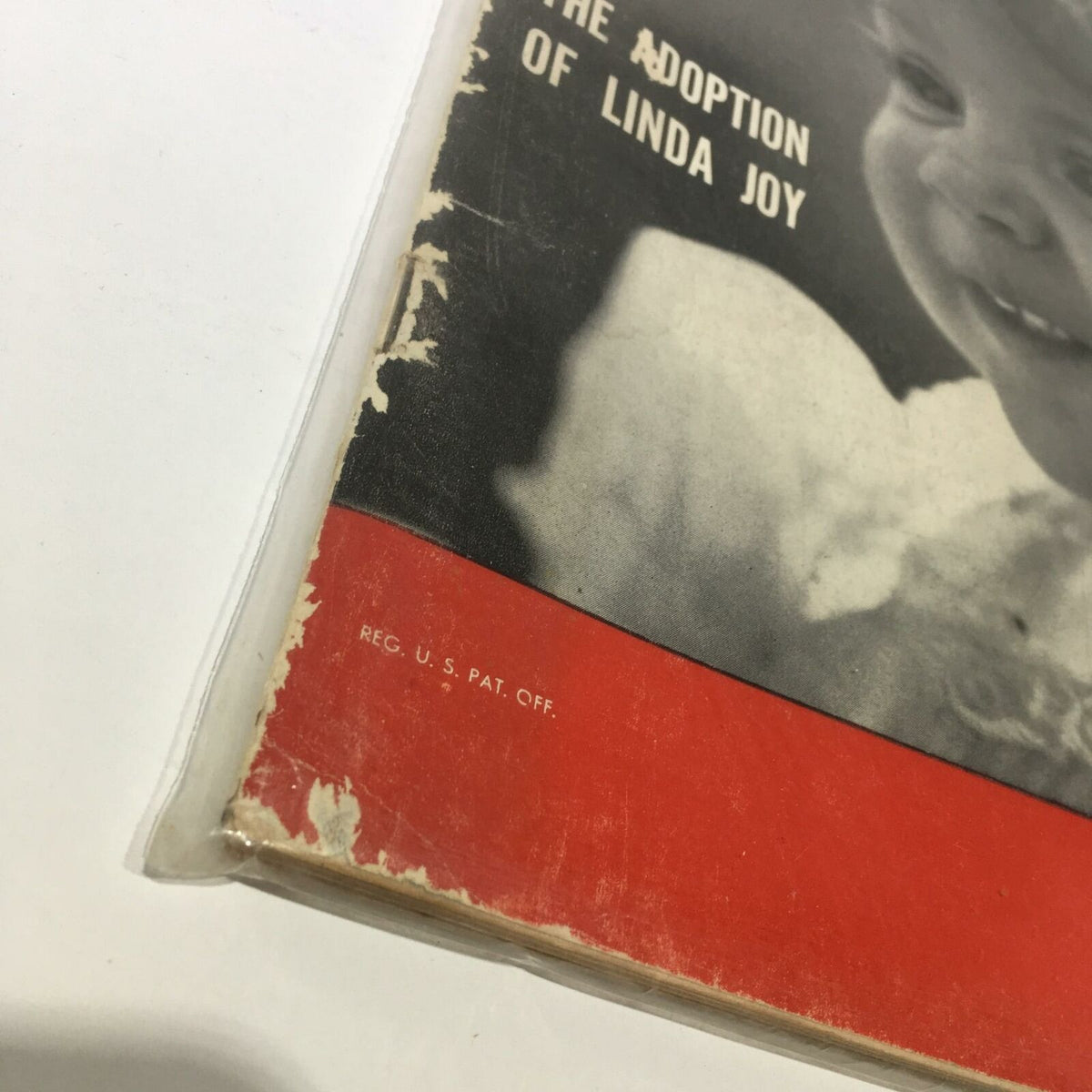 Close-up of the vintage Life magazine from February 19, 1951, titled 'The Adoption of Linda Joy,' showing the edge of the cover with some wear and the text 'REG. U.S. PAT. OFF.' highlighting its collectible nature.
