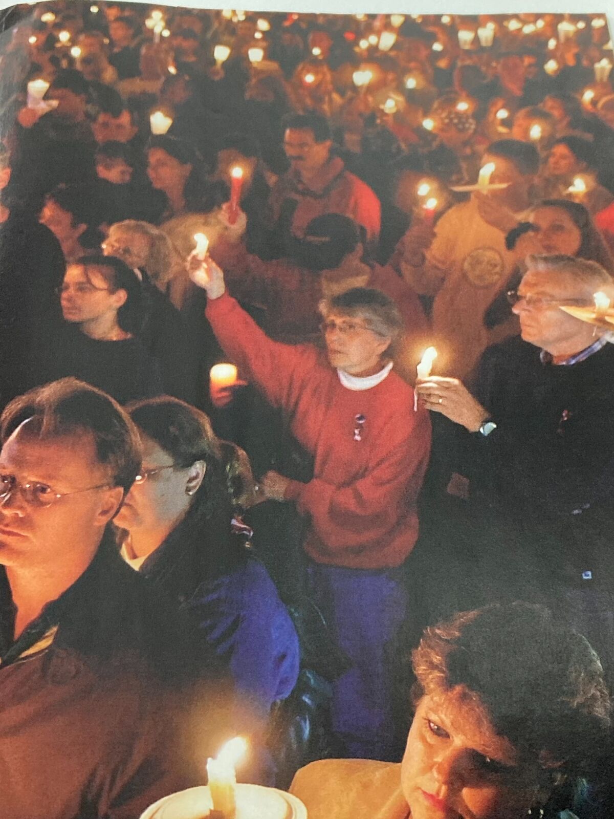 A somber gathering of people holding candles in remembrance following the September 11 attacks, as featured in Time Magazine's September 24, 2001 issue titled "Out of the Ashes".