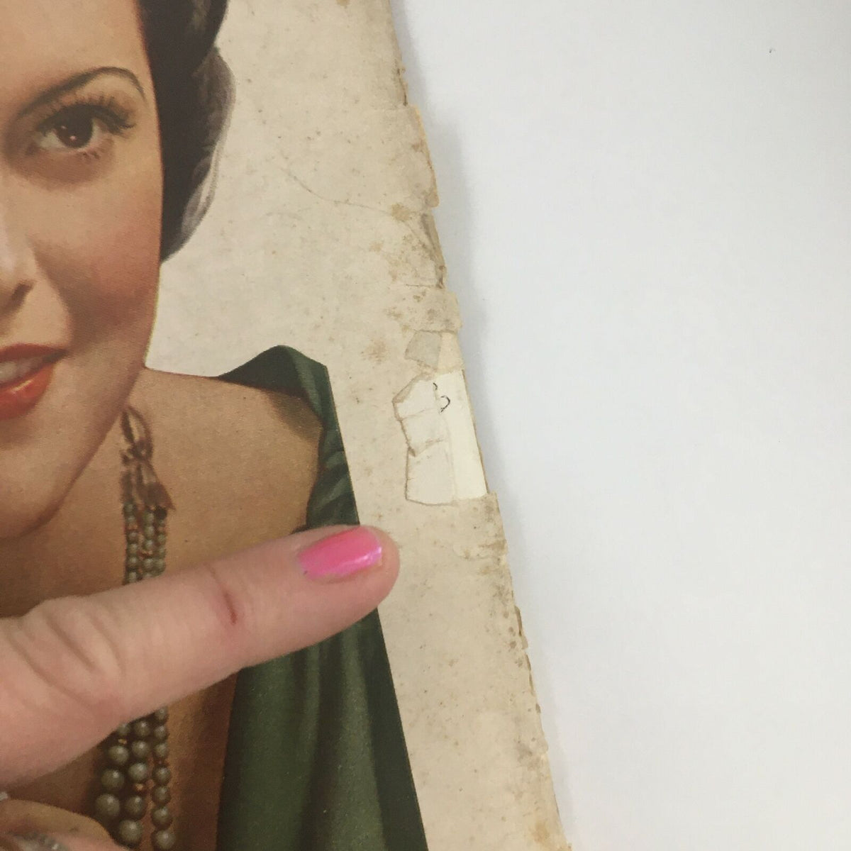 Close-up of the damaged edge of the Time Magazine November 7 1932 cover, highlighting minor wear with a finger pointing towards the imperfection, preserving a historical artifact.