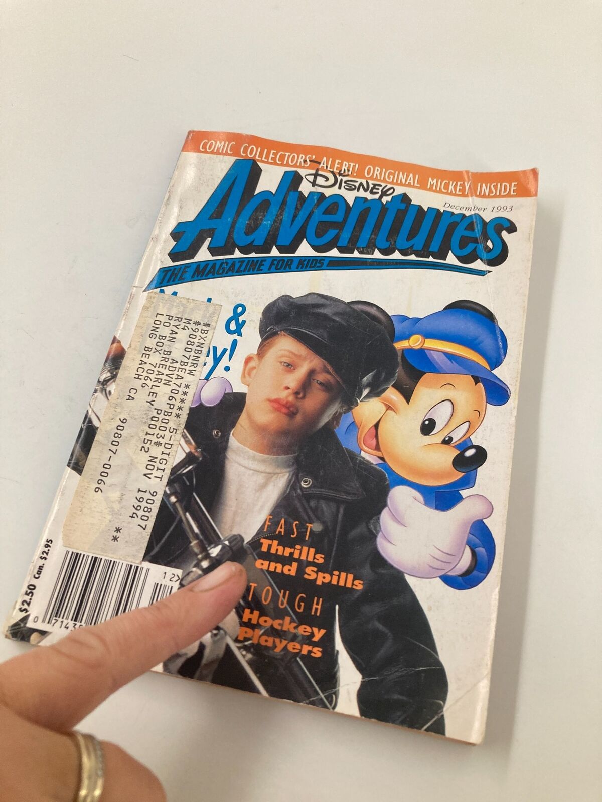 Close-up view of Disneyland Adventures Magazine December 1993 cover showing Macaulay Culkin in a leather jacket next to Mickey Mouse. Highlights include fast thrills and spills.