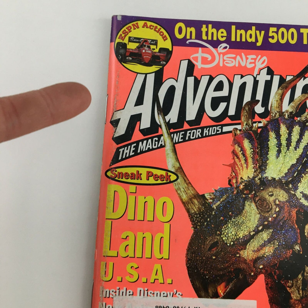 Close-up of the cover of Disney Adventures Magazine May 1998 highlighting 'Sneak Peek Dino Land U.S.A.' with a dinosaur illustration and an ESPN action label.