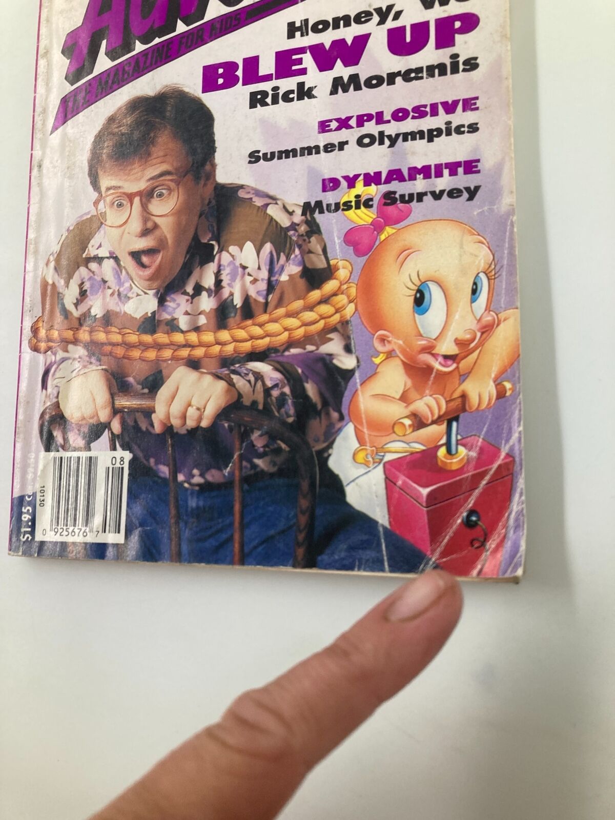 Cover of Disney Adventures Magazine August 1992 featuring Rick Moranis, showcasing a vibrant design celebrating the Summer Olympics. The magazine includes humorous elements and nostalgic imagery.