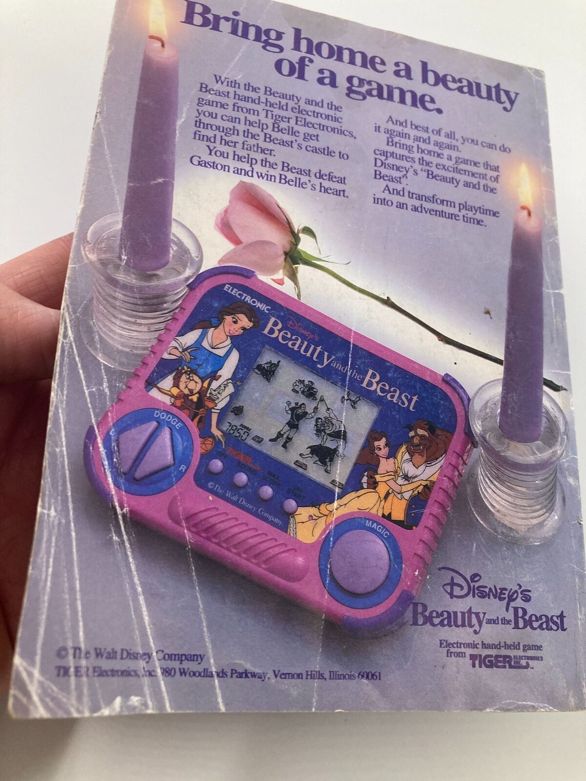 Back cover of Disney Adventures Magazine August 1992 promoting the Beauty and the Beast electronic hand-held game by Tiger Electronics, featuring iconic characters and a whimsical design. This item showcases Disney's enduring appeal.