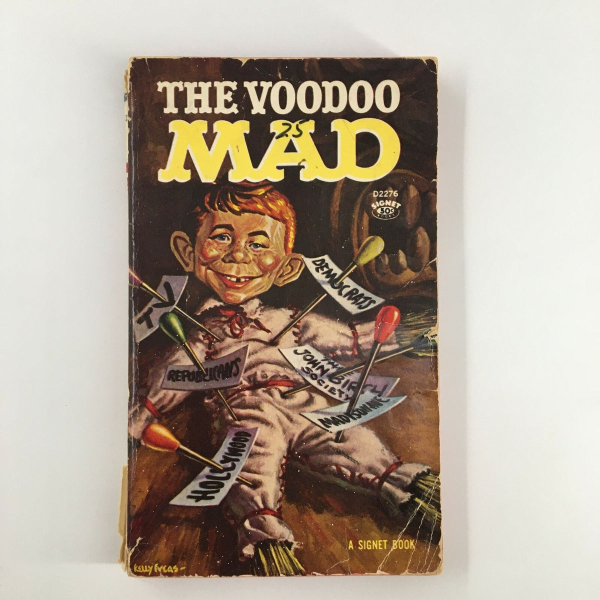 Cover of the 1963 William M. Gaines The Voodoo Mad Signet Book featuring a whimsical illustration of a mischievous child surrounded by voodoo dolls and pins, showcasing its vintage appeal and intriguing design.