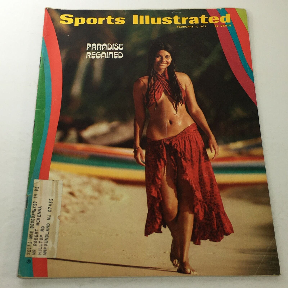 Cover of Sports Illustrated: February 1 1971 - Paradise Regained, featuring a model in a red skirt standing on a beach with colorful canoes in the background.