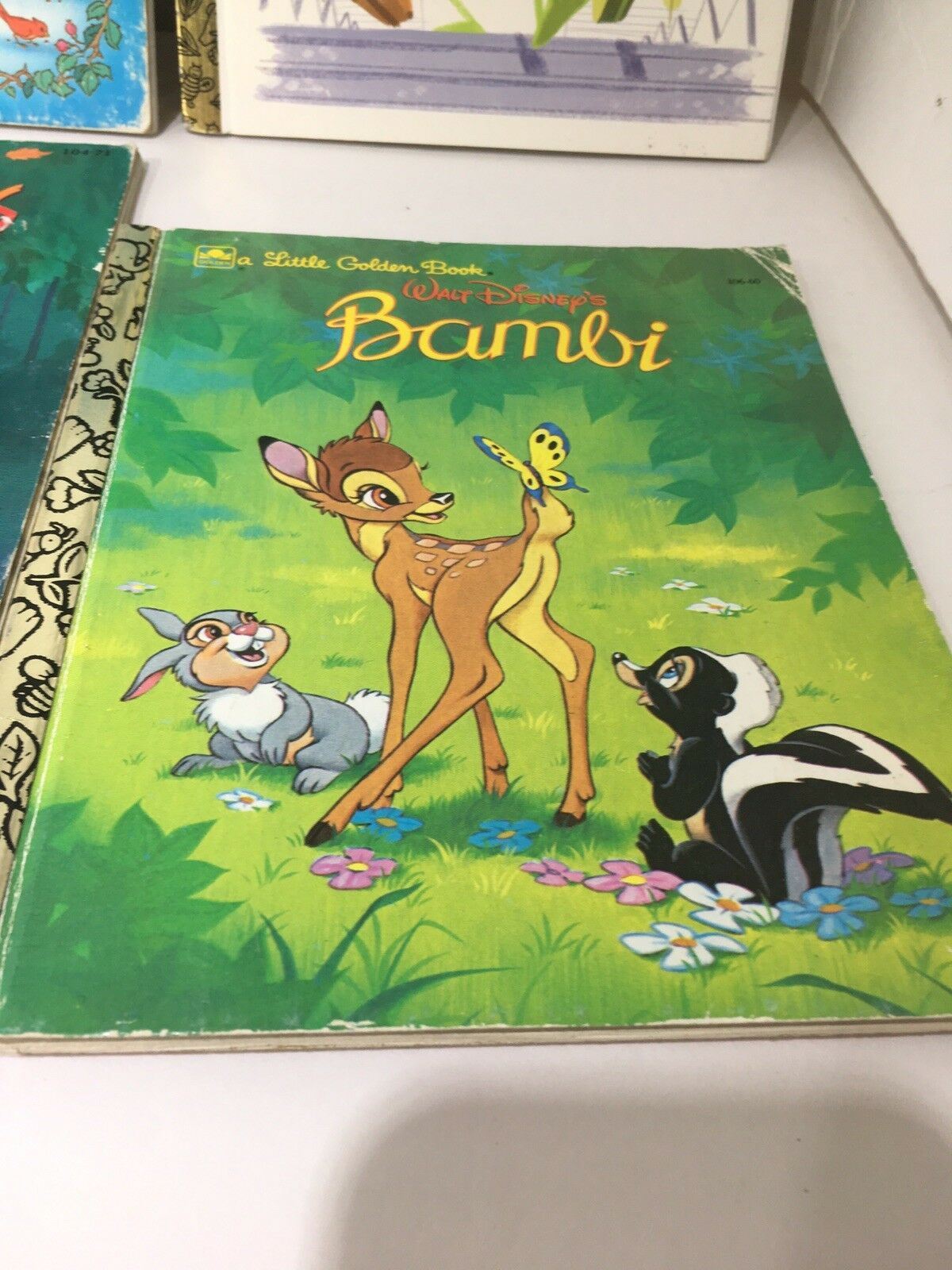Little Golden Book Disney Bambi illustrated cover featuring Bambi with a butterfly, accompanied by a rabbit and a skunk in a lush forest setting.