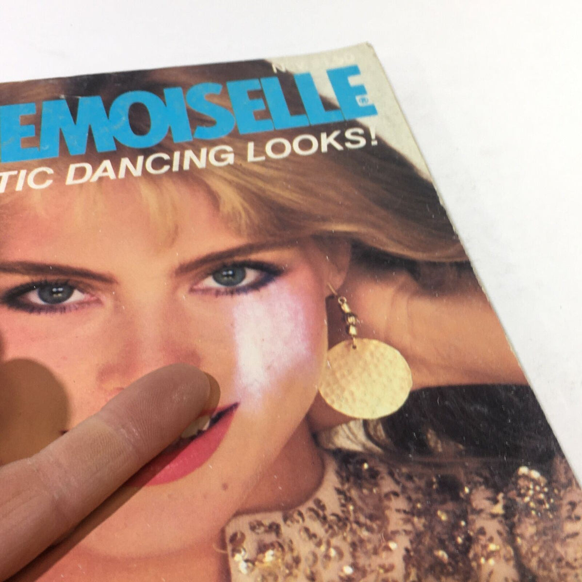 Close-up view of the cover of the VTG Mademoiselle Magazine from November 1980 featuring Kim Alexis. The image showcases the vibrant cover art, highlighting the magazine's title and a detailed look at the model's features, including her accessories and style, reflecting the fashion trends of the early 1980s.