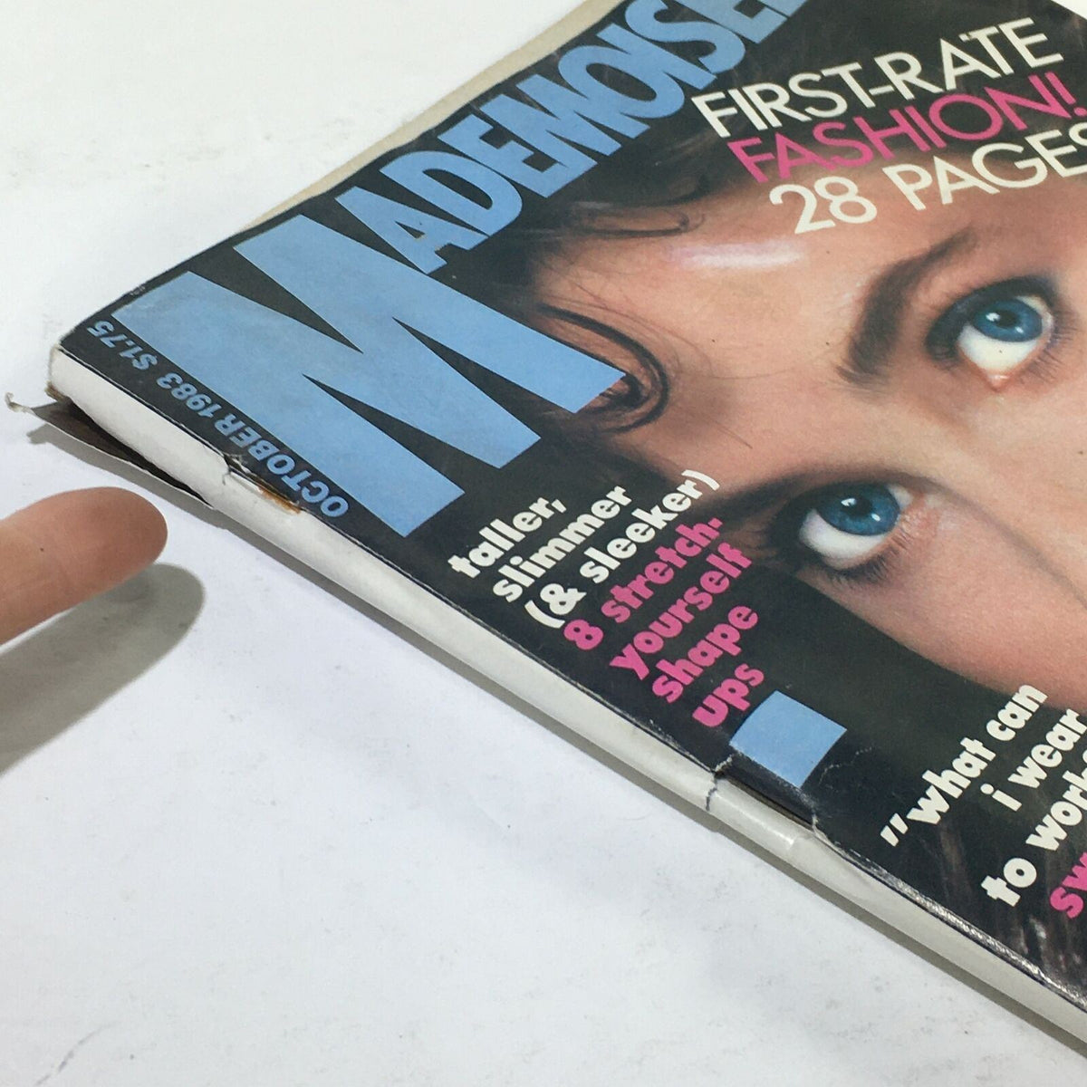 Close-up of the Vintage Mademoiselle Magazine, October 1983 issue featuring a prominent blue 'M' headline and snippets of articles including 'First-Rate Fashion!' and fitness tips. This collectible edition showcases the cover art with Carol Alt, making it a notable piece for vintage magazine enthusiasts.