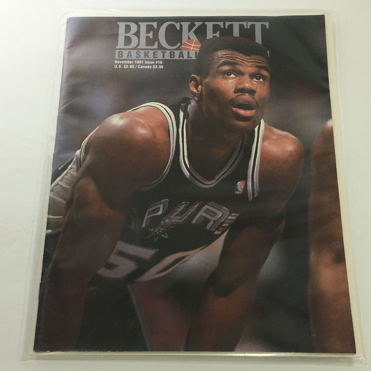 Beckett Basketball Monthly: November 1991 Issue #16 featuring a cover image of Spurs player David Robinson, showcasing his intense focus during a game.