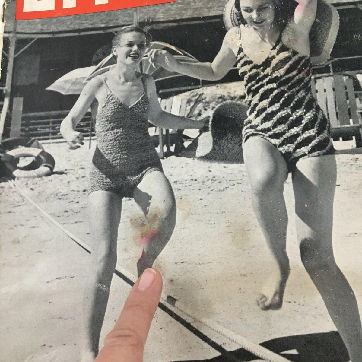 Close-up of the cover of VTG Life Magazine from February 27, 1939, showcasing 'Cruise Girls at Paradise Beach,' with one girl pointing at her leg while both are enjoying a seaside day.