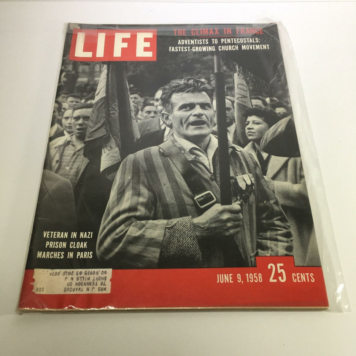Cover of Life Magazine from June 9, 1958 featuring the title 'Veteran in Nazi Prison Cloak Marches in Paris'. The magazine showcases a veteran holding a flag, dressed in a striped prison cloak, symbolizing historical significance and emotional weight. Ideal for collectors and history enthusiasts.