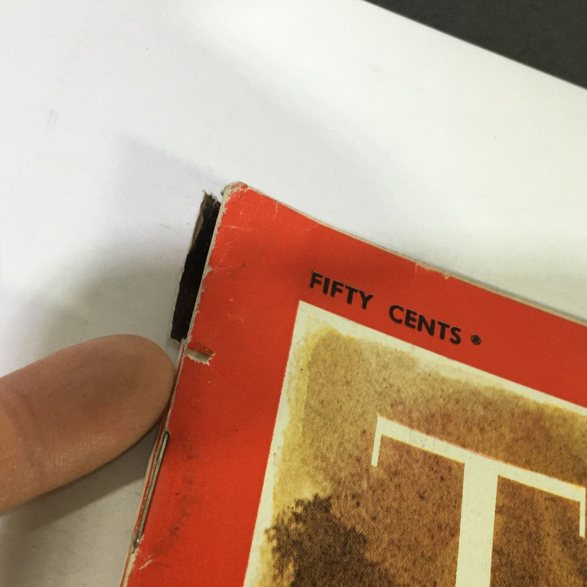 Close-up of the edge of a VTG Time Magazine March 28 1969, showing wear and a small rip, emphasizing the magazine's vintage condition.