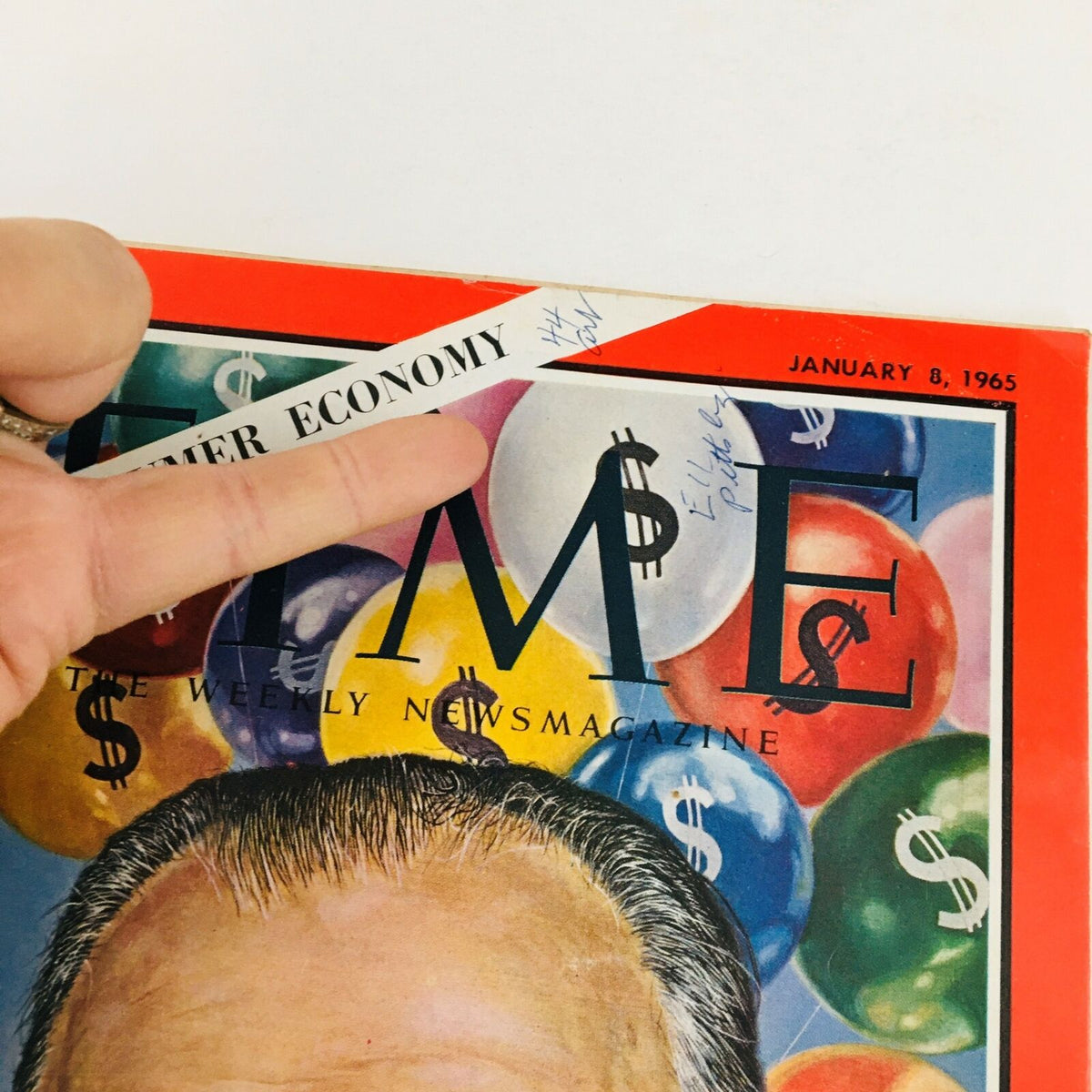 Close-up of the Time Magazine January 8, 1965 cover, highlighting the text 'The Consumer Economy' and a hand pointing at the title, with dollar signs featured in the background.