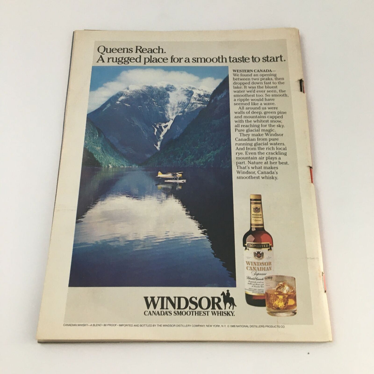 Vintage advertisement showcasing a serene mountainous lake scene with a seaplane and the Windsor Canadian whisky bottle, illustrating the natural beauty of Western Canada, VTG Time Magazine September 8 1986.