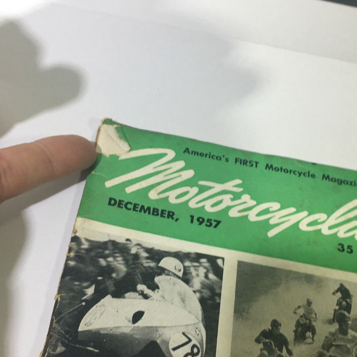 Close-up of the Vintage Motorcylist Magazine December 1957 cover showing minor wear and tear, highlighting its collectible nature.