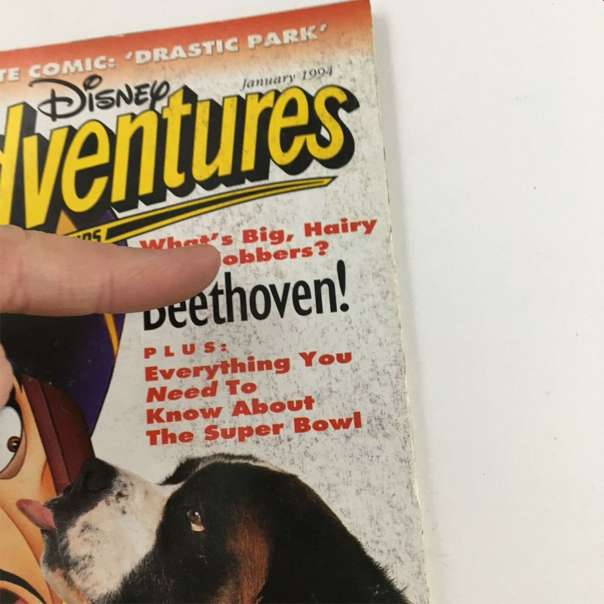 Close-up of Disney Adventures Magazine January 1994 cover, highlighting the titles about Jafar, Beethoven, and the Super Bowl, with finger pointing to the text.