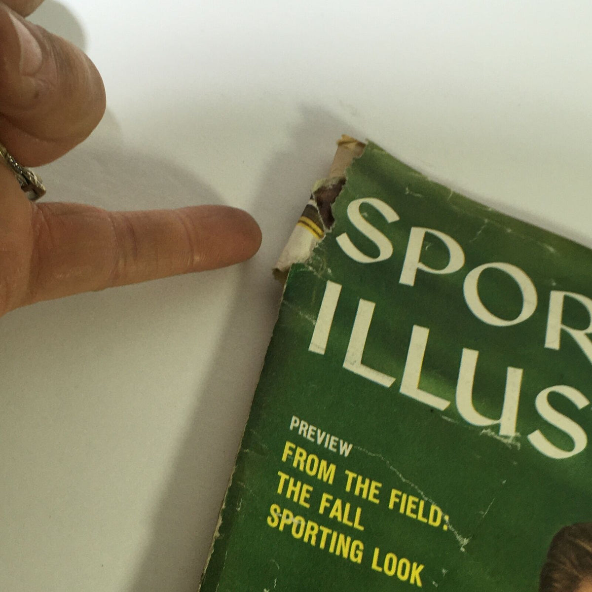 Close-up view of the corner of the vintage Sports Illustrated magazine, showing wear and tear from 1959, featuring U.S. Amateur Charlie Coe.