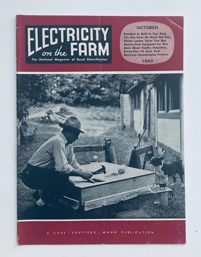 Cover of the VTG Electricity on the Farm Magazine from October 1943, showcasing a farmer working on a brooder construction with tools, alongside a dog. The magazine emphasizes rural electrification and features articles on brooder building techniques.