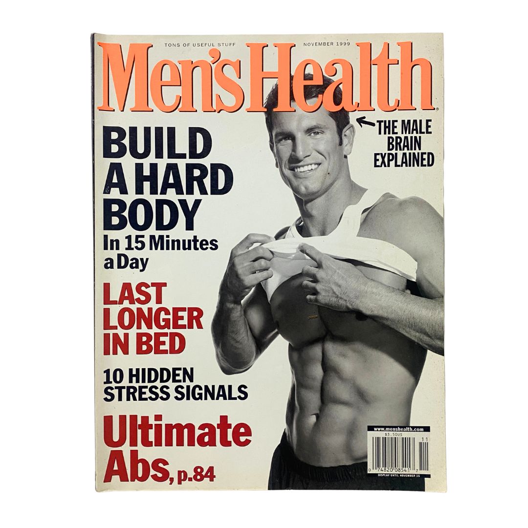 Men's Health Magazine cover from November 1999 titled 'The Male Brain Explained', featuring an image of a muscular man showing his abs, with bold headlines about fitness and health, including topics like building a hard body and stress signals.