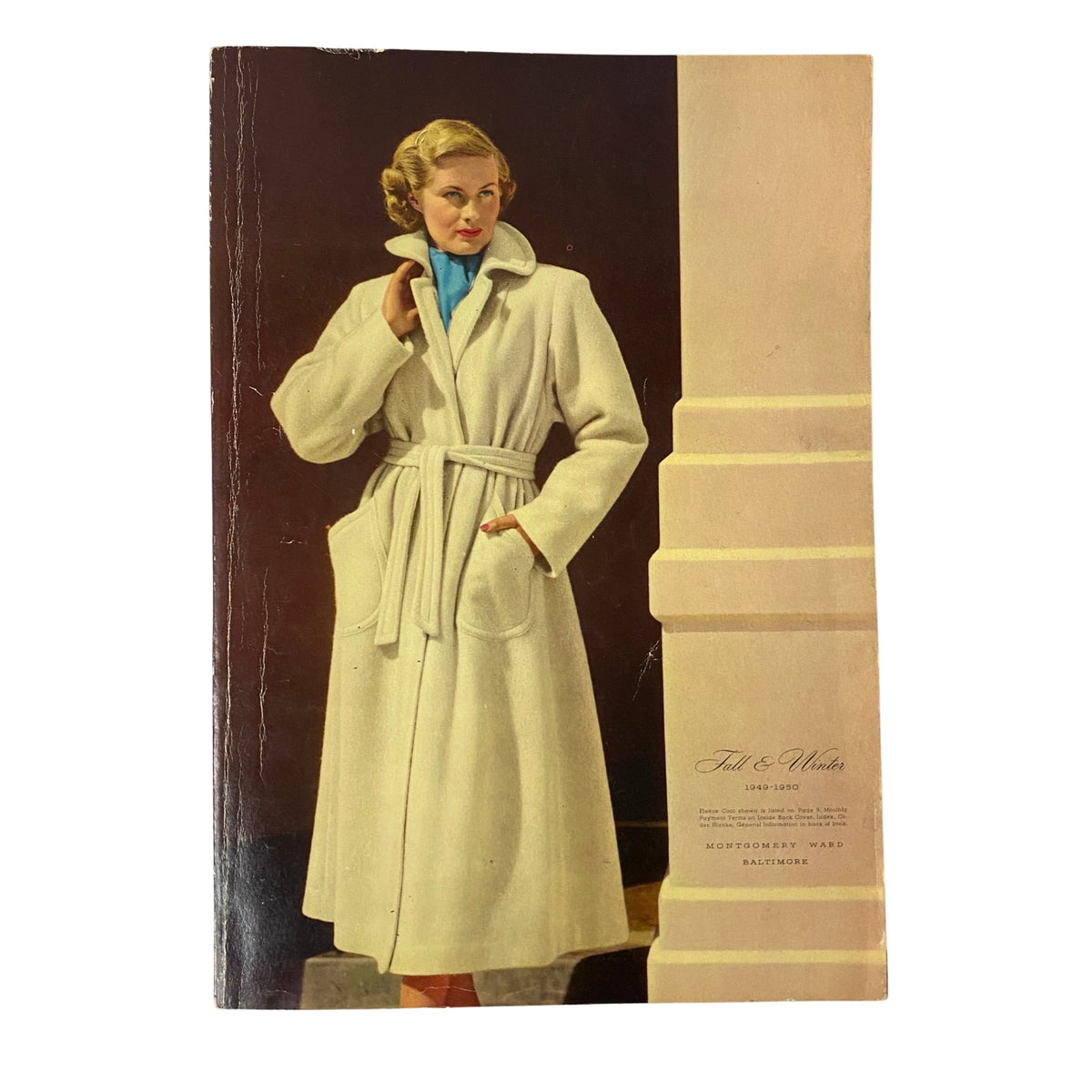 Cover of the 1949-1950 Montgomery Ward Baltimore Fall and Winter Catalog featuring a woman in a white wool coat with a belt, showcasing vintage fashion from the post-war era.