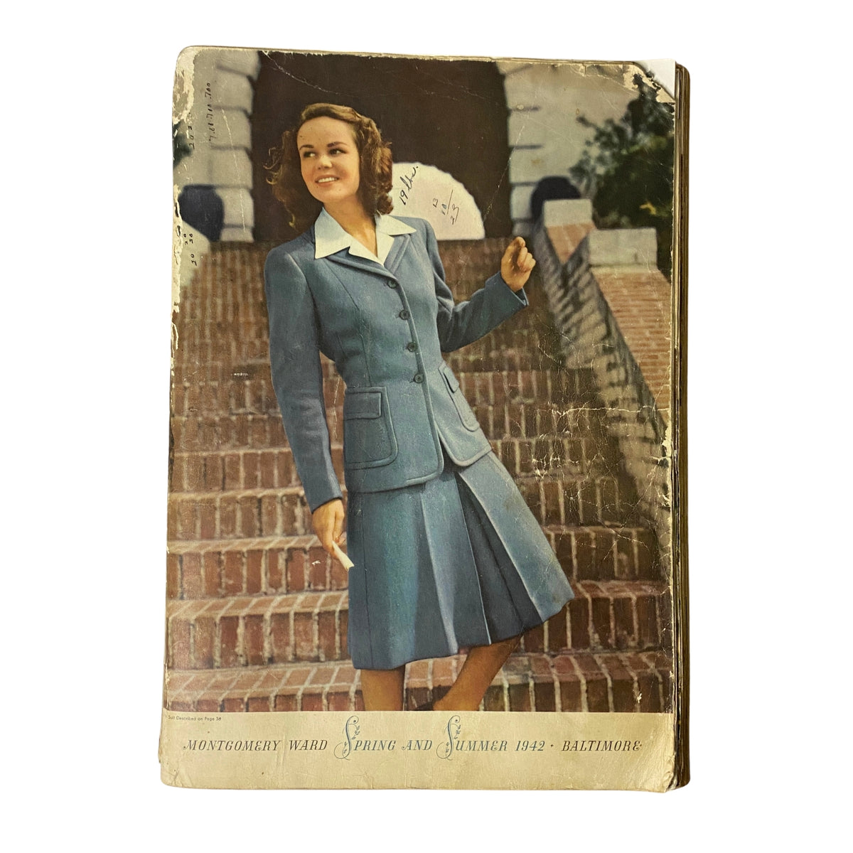 1942 Montgomery Ward Spring and Summer Catalog cover featuring a woman in a stylish blue suit with white collar, standing on stairs.