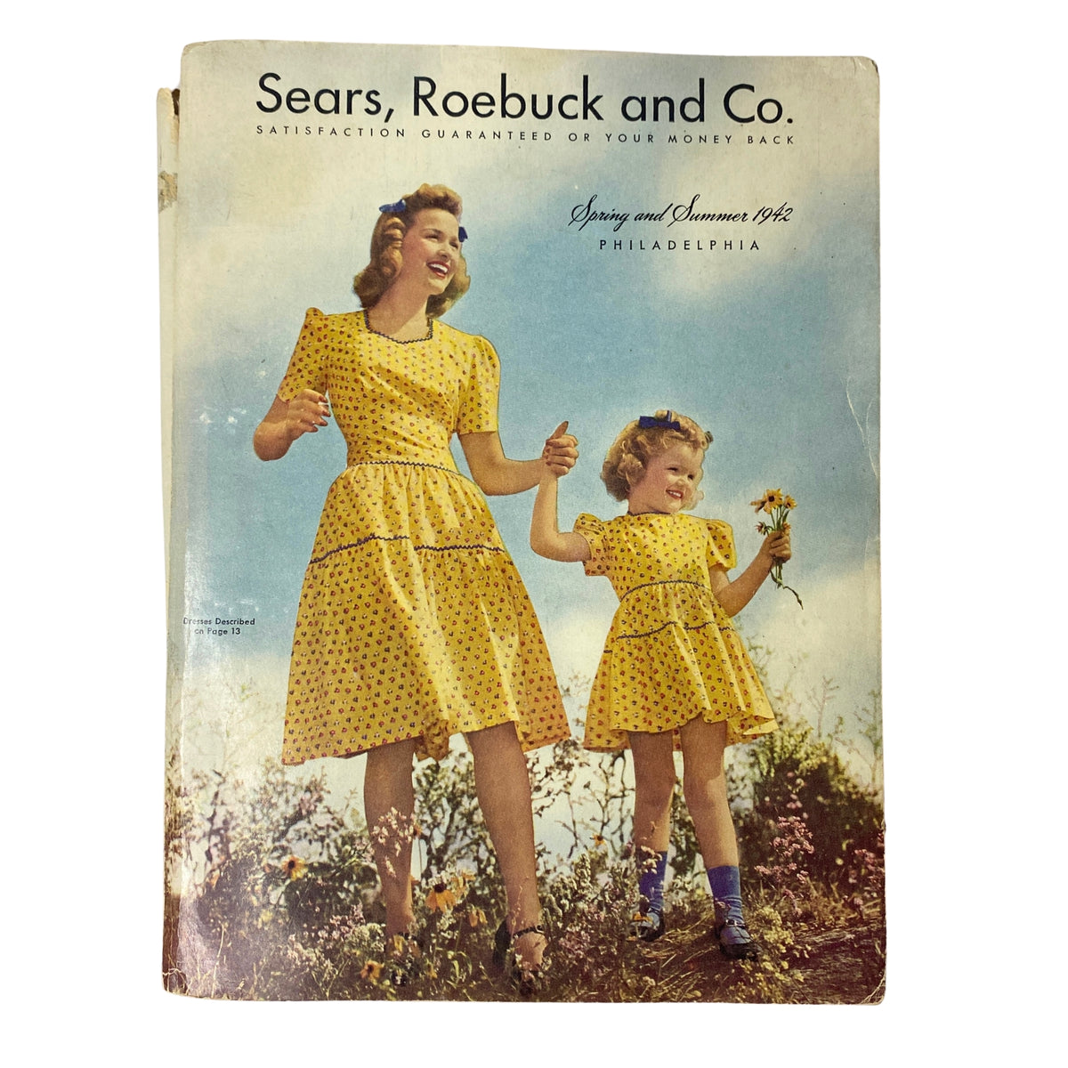 Cover of the 1942 Sears, Roebuck and Co. Spring and Summer Catalog featuring a woman and a girl wearing matching yellow dresses in a natural setting, highlighting vintage fashion from the World War II era.