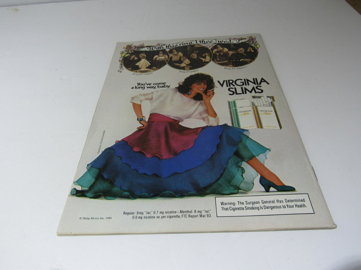 A vintage advertisement page from the 1984 US Magazine featuring Virginia Slims, showcasing a stylish woman in a colorful outfit. This ad captures the essence of 1980s fashion and culture.
