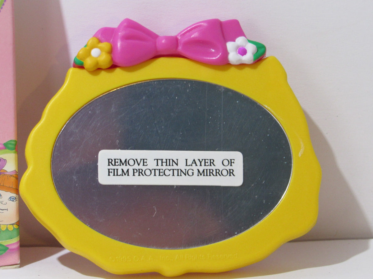 Back view of the 1995 Rare Avon Cabbage Patch Kids Portable Comb and Mirror Compact, showing the mirror with a protective film.