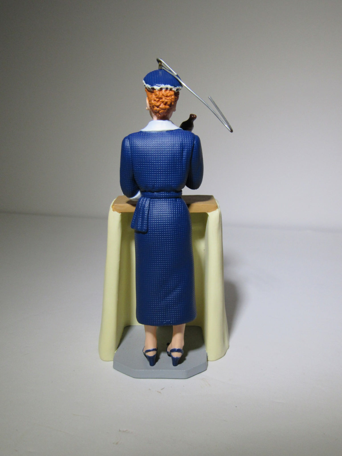 Back view of a 2001 Hallmark Keepsake Ornament featuring I Love Lucy's VitaMeataVegamin character, showcasing details of the outfit and hair.