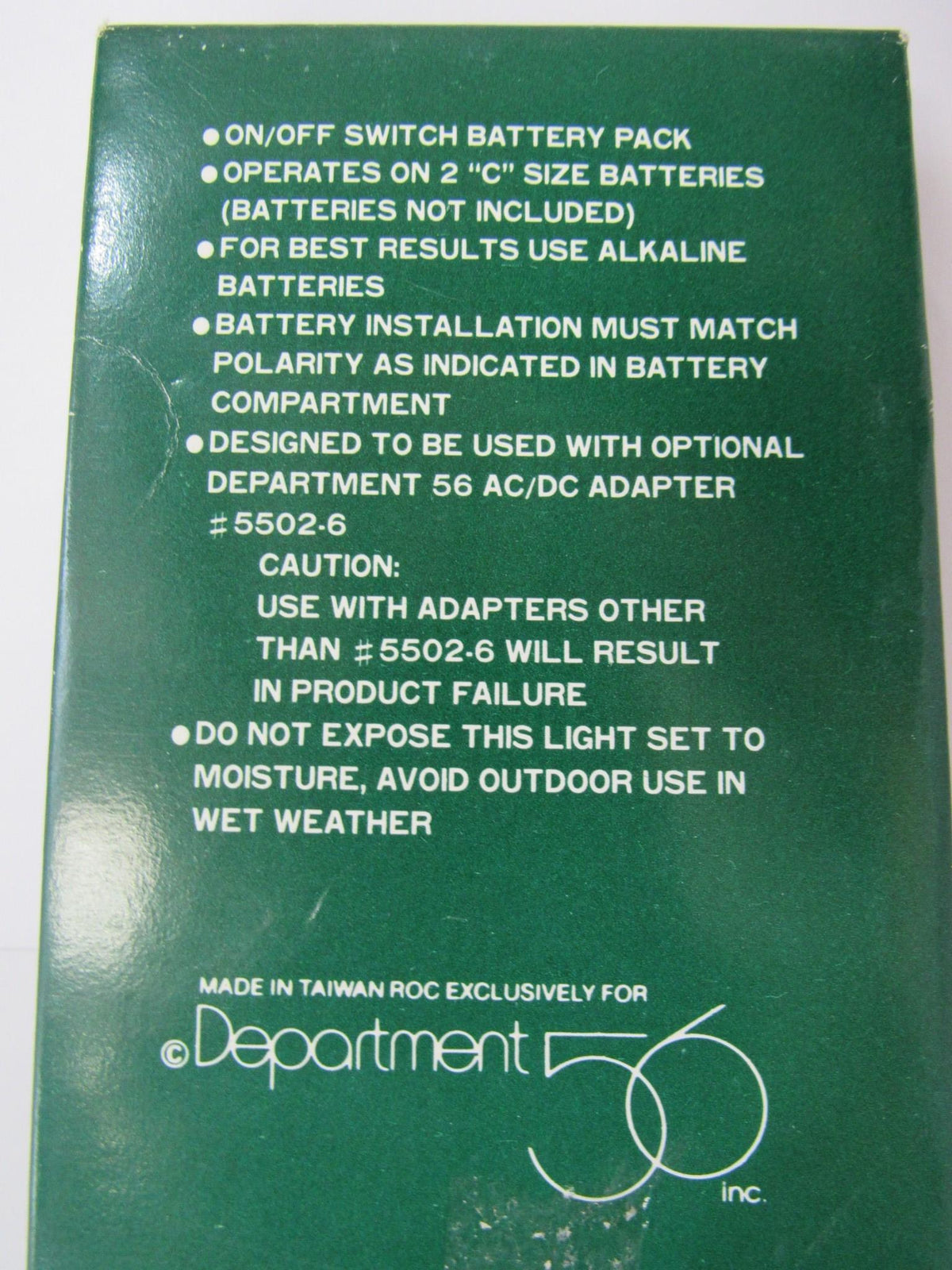 Back view of the Department 56 Village Railroad Crossing Signal #5501-8 packaging, detailing battery operation information and usage instructions.