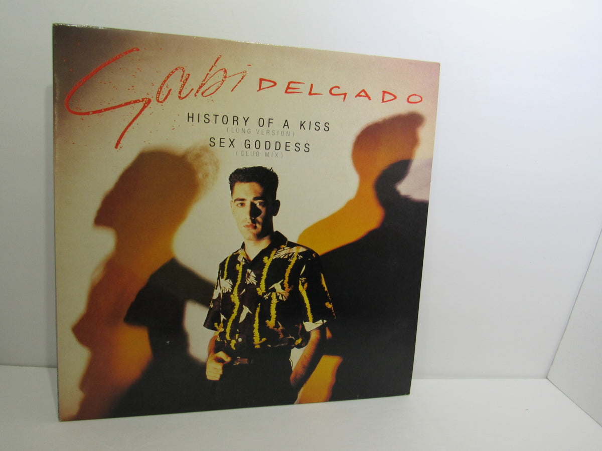 Cover art for Gabi Delgado: History Of A Kiss featuring the album title and artist with a vintage photo of the artist under dramatic lighting.