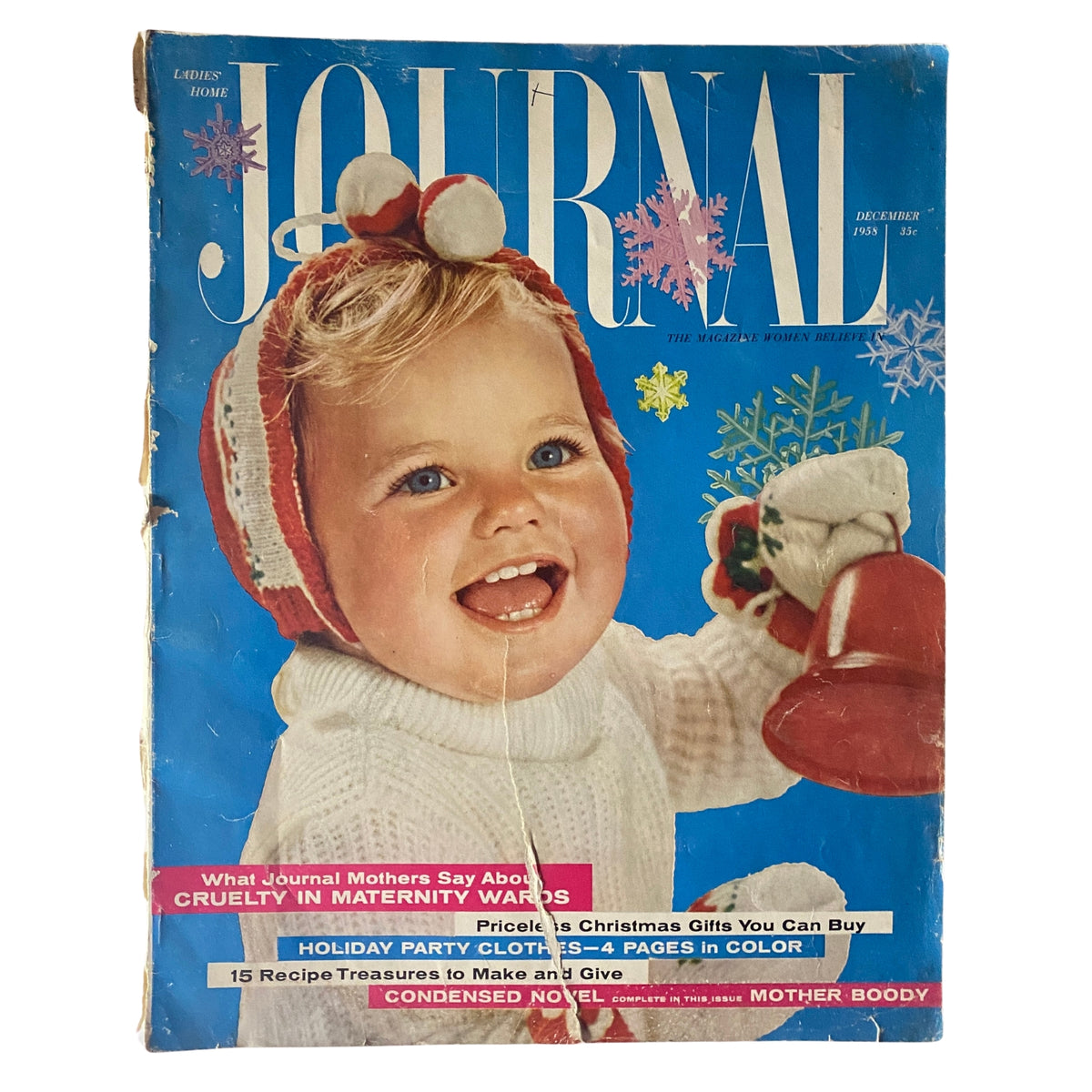 Ladies' Home Journal Magazine December 1958 cover featuring a joyful baby in a festive winter sweater holding a bell, showcasing the issue's themes of holiday celebration and family.